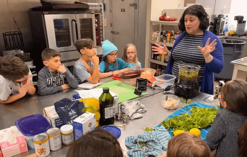adult leading students in a cooking class